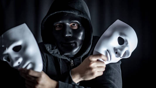 蒙面人神秘的蒙面人戴着黑色面具,手里拿着两个白色面具.