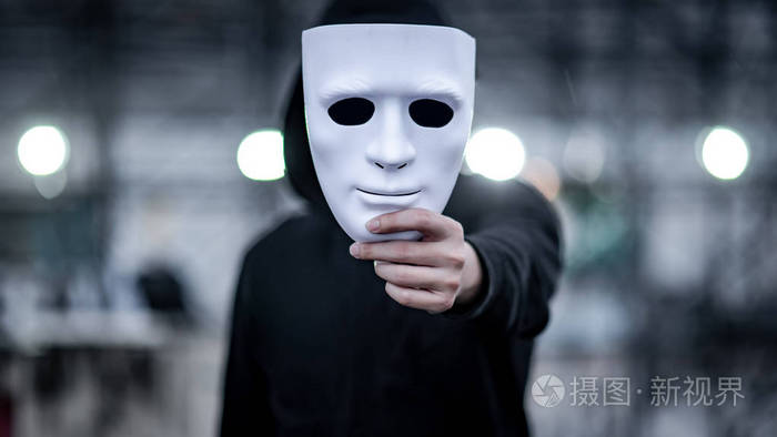 神秘的帽衫男人带着黑色面具手里拿着白色面具匿名社会掩蔽或双相情感