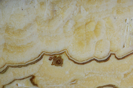背景从一个浅黄色的天然石头红玛瑙与气泡和污渍在表面被称为冰阿科虹膜。
