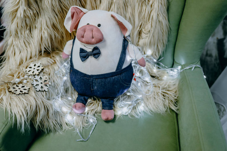 干草背景上美丽的毛绒小猪被圣诞花环包围着