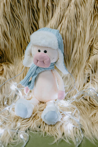 干草背景上美丽的毛绒小猪被圣诞花环包围着