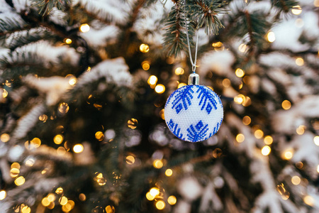 蓝白色圣诞球在杉树枝上，关闭金黄色的灯光，背景