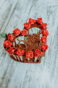 一份不寻常的礼物，送给一个可爱的人，形状像一颗心，由新鲜的花朵组成，玫瑰，郁金香，干花，在透明的玻璃瓶中。 木制材料制成的浅色背