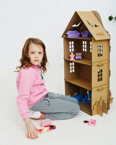 快乐的女孩玩纸板娃娃屋。 有趣可爱的孩子