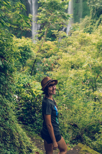 在印度尼西亚巴厘岛的热带雨林中, 年轻女子在一个伟大的塞库姆普尔瀑布上摆姿势