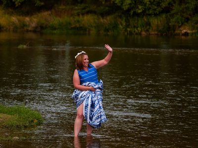 一位穿着蓝色派对礼服的河中欢快的年轻女子的肖像。