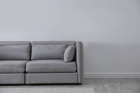 简单的客厅内部，舒适的沙发靠近轻质墙壁。 文本空间