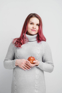 一位孕妇拿着绿色和红色的苹果
