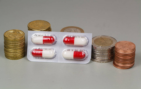 一堆欧元硬币和一包白色和红色药丸