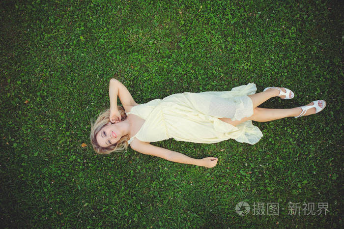 美丽的年轻女子躺在草地上新鲜的自然夏季概念从上面看图像