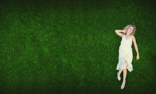 美丽的年轻女子躺在草地上。 新鲜的自然夏季概念。 从上面看。 图像