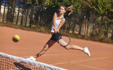 一个女孩在晴朗的天气在球场上打网球