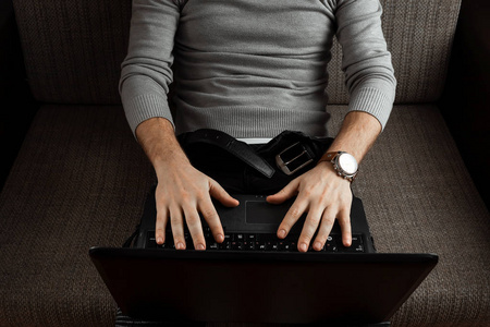 一个年轻人在笔记本电脑上工作，穿着牛仔裤在家舒适的沙发上放松。 自由职业者在家工作的概念，为自己的自我就业，创业在线业务。