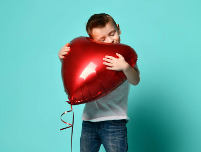 小男孩爱拿大红心气球在流行的绿色薄荷背景上庆祝情人节