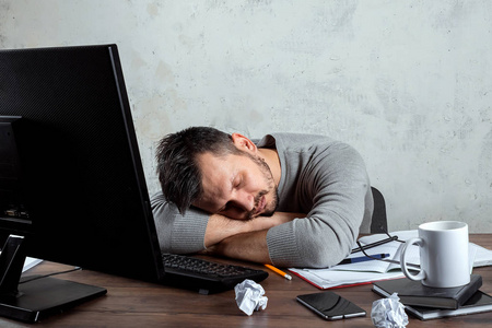 一个男人，一个睡在办公室桌子旁的人。 办公室工作的概念很多工作疲劳懒惰。 复制空间。