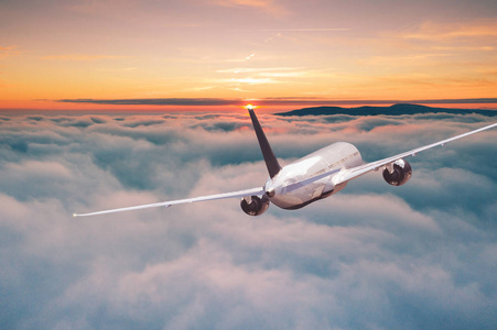 云层上日出商用飞机客机在戏剧性的云层上飞行照片