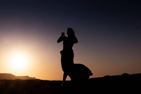 女人跳着著名的阿拉伯肚皮舞。 在纳米比亚干旱的沙漠平原上日落。 非洲。 安哥拉。
