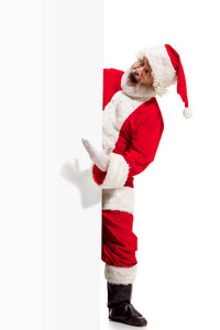 愉快的圣诞老人指向空白广告横幅背景与拷贝空间。微笑的圣诞老人指向白色空白标志
