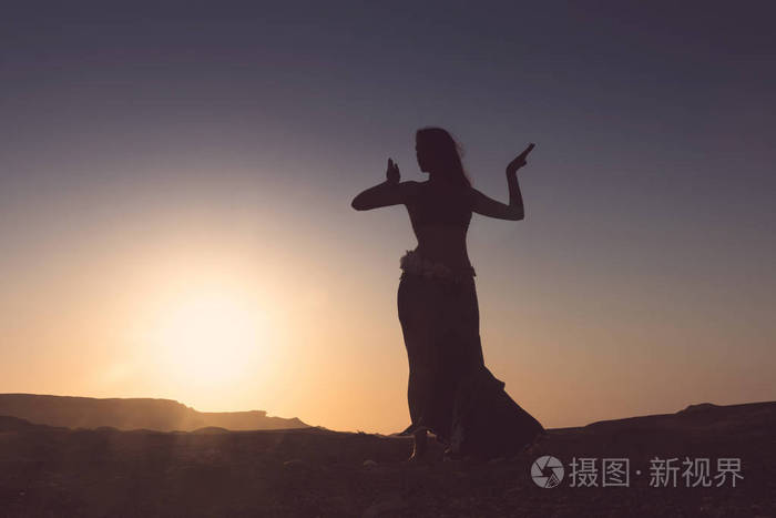女人跳着著名的阿拉伯肚皮舞在纳米比亚干旱的沙漠平原上日落非洲