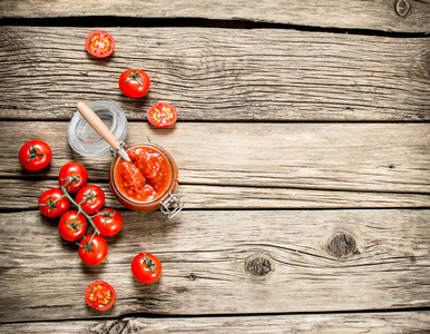 番茄酱在一个装有新鲜西红柿的玻璃罐子里。 在木制的背景上。