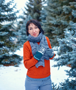 女人在冬天的森林里摆姿势，美丽的风景和雪杉树。 穿着红色毛衣