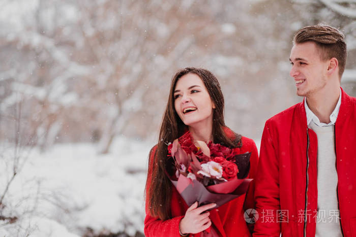 冬天和我的公园有情人的约会。一束红花, 散步, 拥抱, 亲吻, 在浪漫的环境中大笑。一对夫妇的肖像, 丈夫和妻子。红色夹克和外套