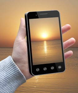 现代智能手机，屏幕上的日落图像在手。 人手中显示自然图像的手机。 现代通信