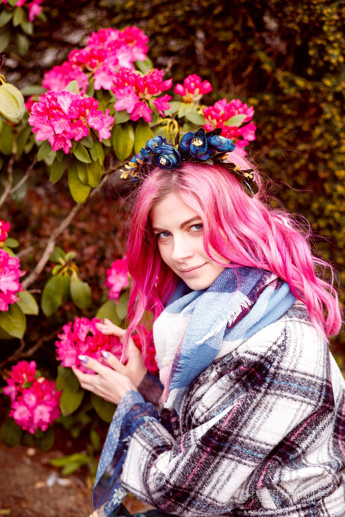 一个美丽的女孩的肖像,粉红色的头发站在粉红色的花朵附近.