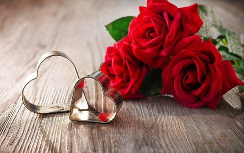 情人节的抽象背景，红玫瑰和木桌上的两颗心