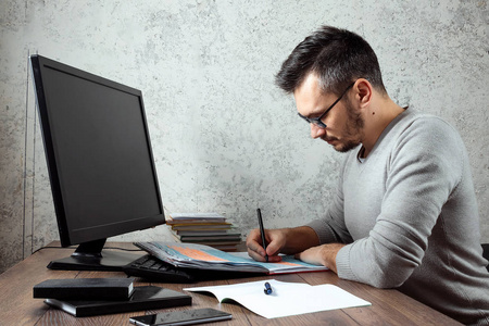 一个男人，一个坐在办公室的桌子上写重要文件的人。 办公室工作的概念。 复制空间。