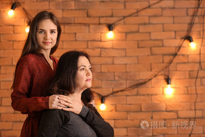 年轻女子和母亲靠砖墙的肖像