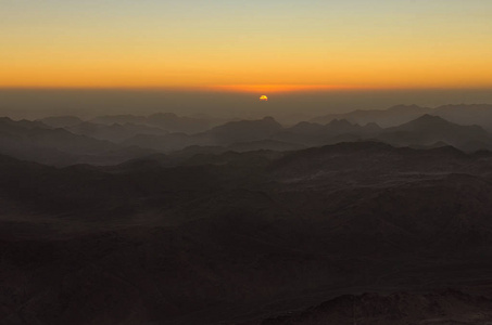 山上令人惊叹的金色日出。 太阳从云层里出来。 从西奈山霍雷布加巴尔穆萨摩西山观看。 埃及的西奈半岛。