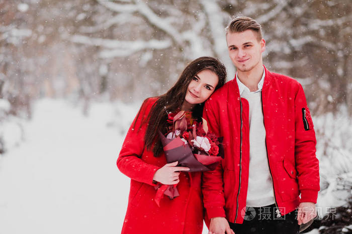 冬天和我的公园有情人的约会。一束红花, 散步, 拥抱, 亲吻, 在浪漫的环境中大笑。一对夫妇的肖像, 丈夫和妻子。红色夹克和外套