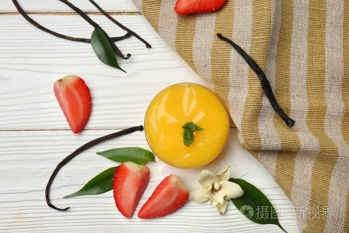 在白色木桌上放美味的香草布丁和草莓