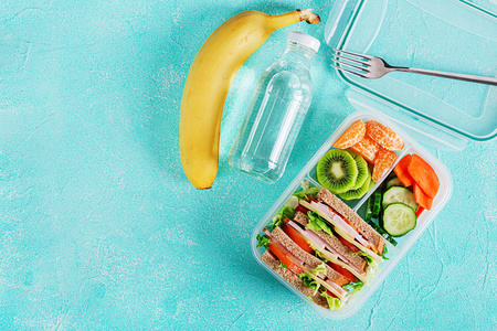 学校午餐盒，桌上有三明治蔬菜水和水果。 健康的饮食习惯概念。 平躺着。 顶部视图