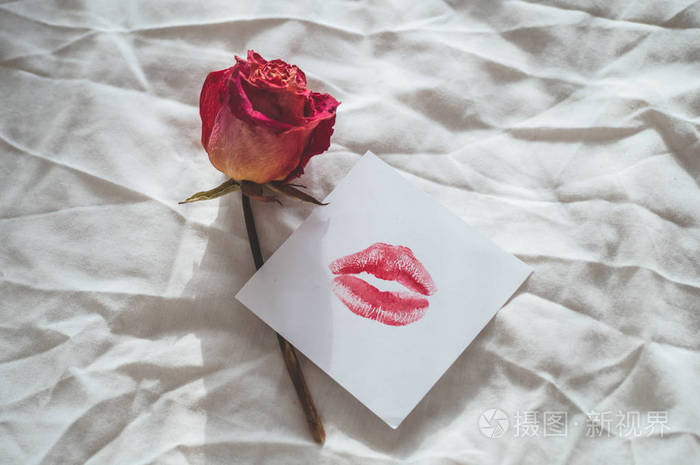 一个音符与亲吻和干燥的玫瑰在一张白色的床上情人节概念