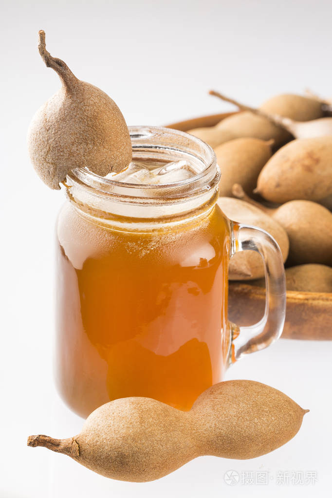 一杯中的罗望子汁被新鲜成熟的罗望子包围