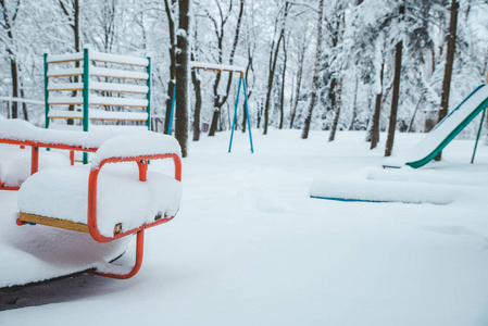 被雪覆盖的操场。 冬季。 儿童旋转木马关闭。 下雪