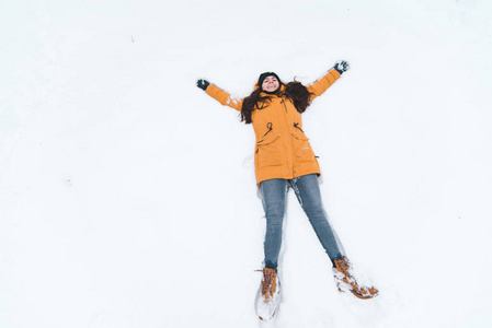 年轻的成人微笑的女人做雪天使图片