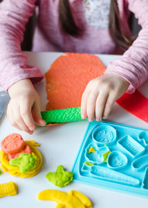 s hands with colorful clay. Child playing and creating vagetable