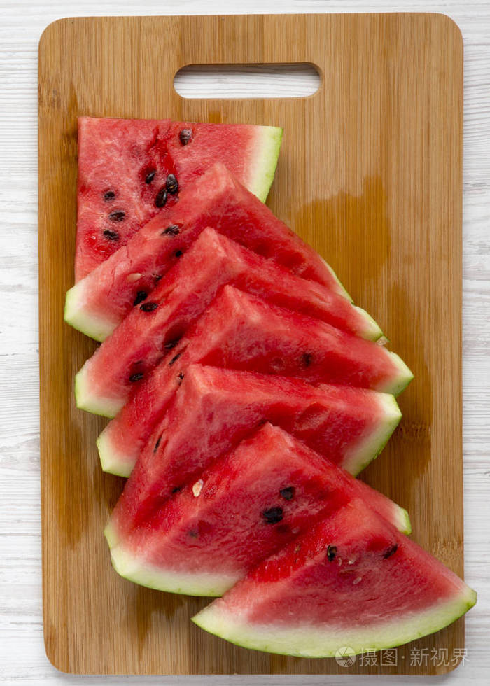 切片西瓜在竹板上的白色木制表面顶部视图. 从上面平躺在上面.