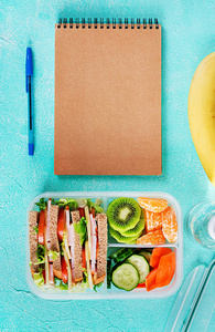 学校午餐盒，桌上有三明治蔬菜水和水果。 健康的饮食习惯概念。 平躺着。 顶部视图
