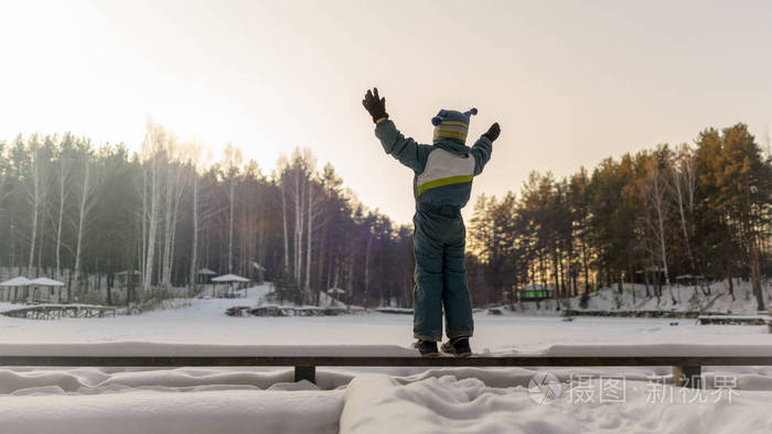 冬天，在冰冻的湖面上，男孩享受阳光，举起双手