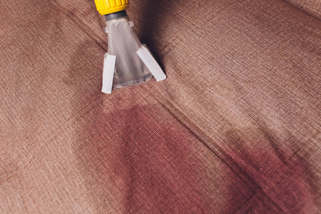 沙发化学清洗采用专业提取方法。软垫家具。早春清洁或定期清洁。干洗店在轻型防护手套员工去除污垢