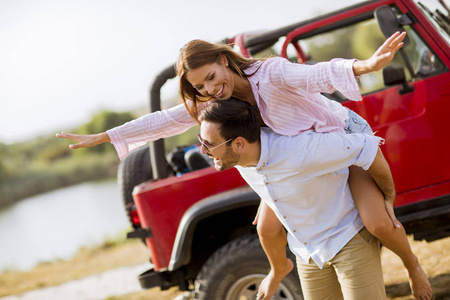 一个年轻的女人和男人在夏日的汽车附近玩得很开心