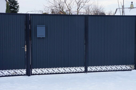 雪屏障在白雪覆盖的街道上,灰色的封闭金属大门照片