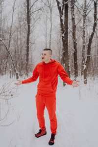 在冬天的森林里，在白雪和树木的背景下摆姿势的疯子。一个穿着红色运动服在新鲜空气中行走的人。概念在寒冷的户外散步和训练