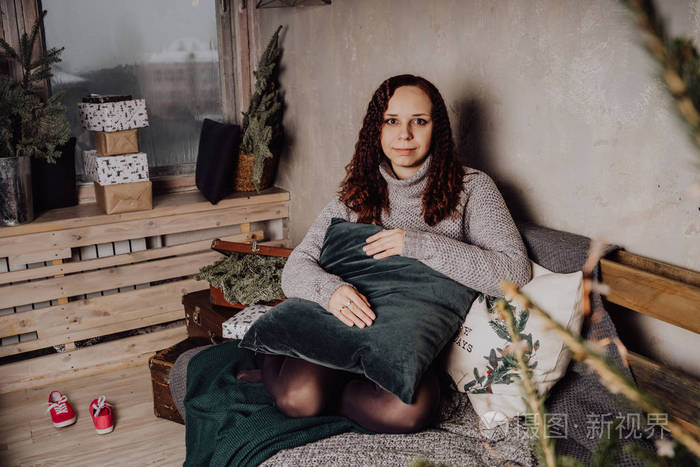 一个穿毛衣的年轻女孩坐在床上蜷缩在毯子里女人穿着温暖的毛衣街头