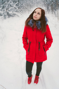 穿着红色夹克在树林里散步的女孩。 概念在新鲜的冬季空气中散步