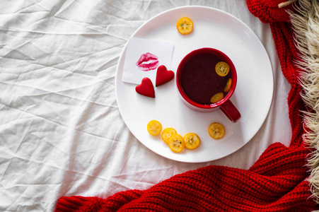 红茶配库姆夸特和两颗心饼干, 一张纸条, 上面有一个吻在白色的床上。情人节概念